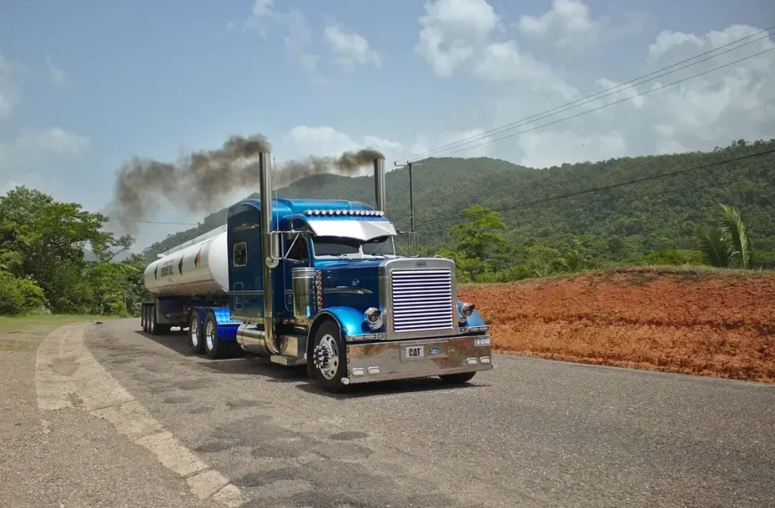 Diesel pickup towing a large trailer uphill on a mountain highway at sunset