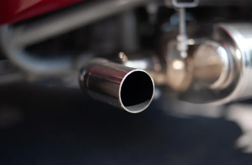Motorcycle rider and mechanic inspecting an exhaust setup beside a sport-touring bike in natural light