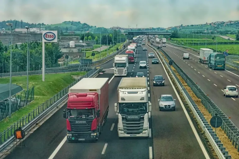 Heavy-duty truck towing a trailer on a highway with the exhaust visible under the rear quarter