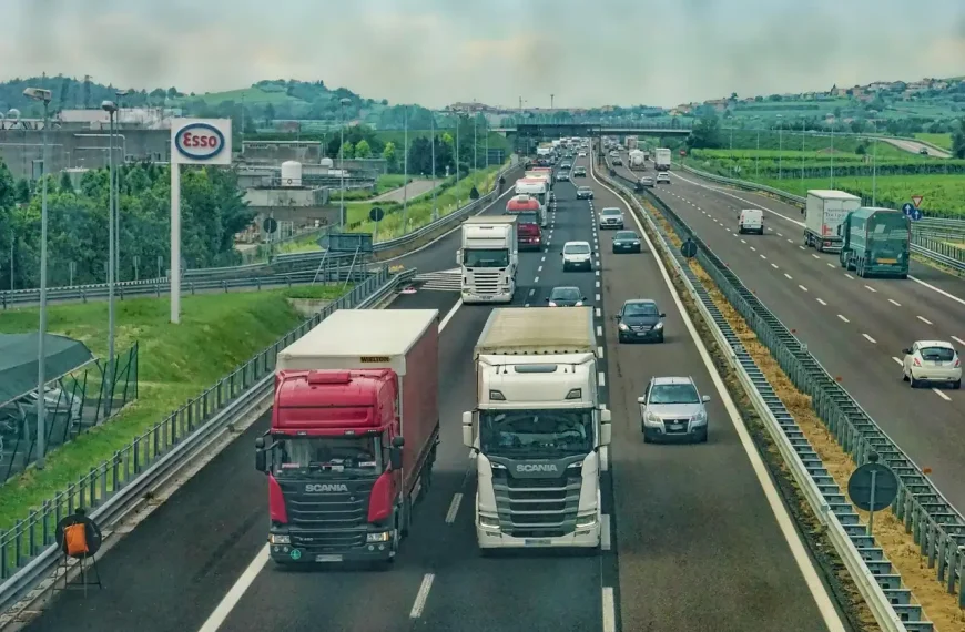 Heavy-duty truck towing a trailer on a highway with the exhaust visible under the rear quarter