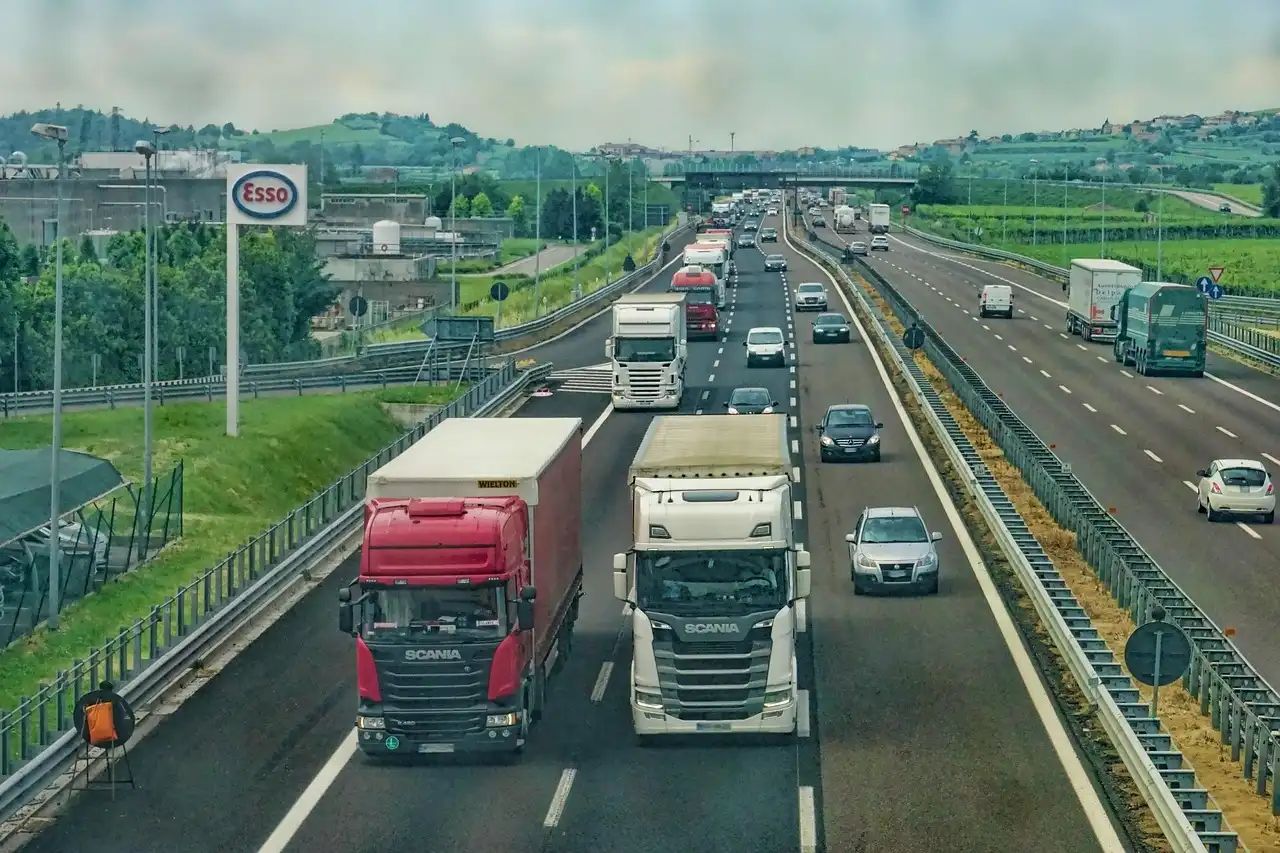 Heavy-duty truck towing a trailer on a highway with the exhaust visible under the rear quarter