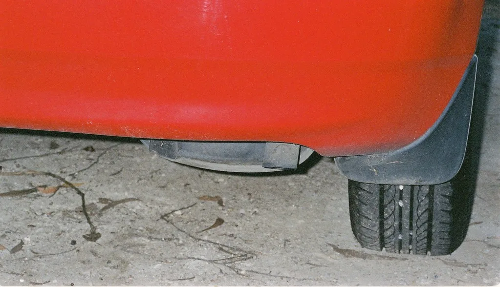 Close-up of a stainless exhaust resonator and mid-pipe on a car lift
