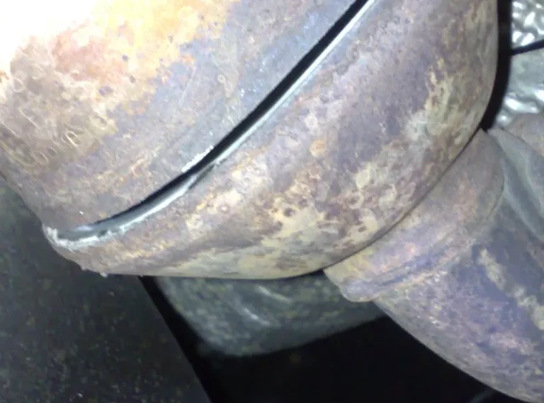 Mechanic inspecting a catalytic converter on a workbench beside a scan tool