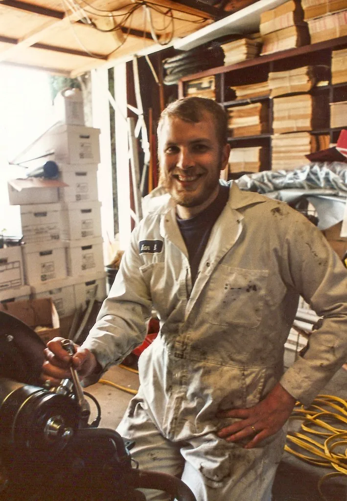 Gloved hand polishing a shiny exhaust tip beside a soot-marked black tip