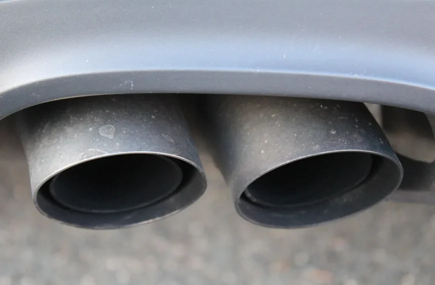 Turbocharged sedan on a lift with a mechanic comparing catted and catless downpipes.