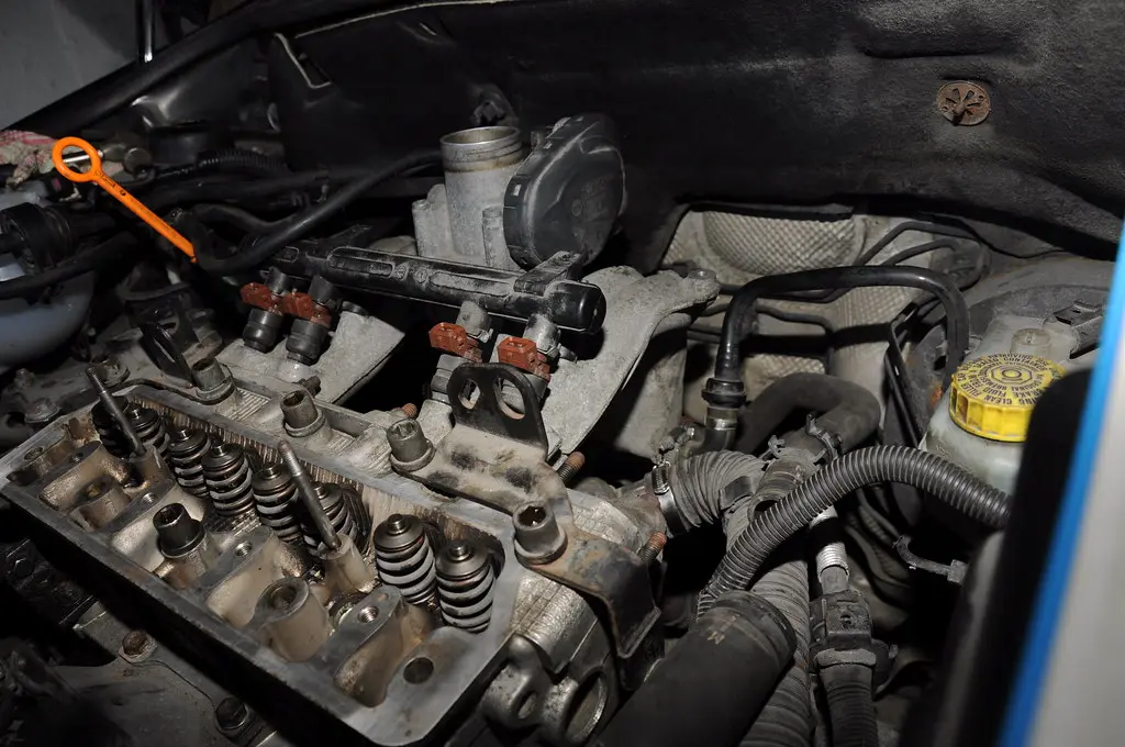 Close-up of a diesel particulate filter and exhaust piping with mechanic hands