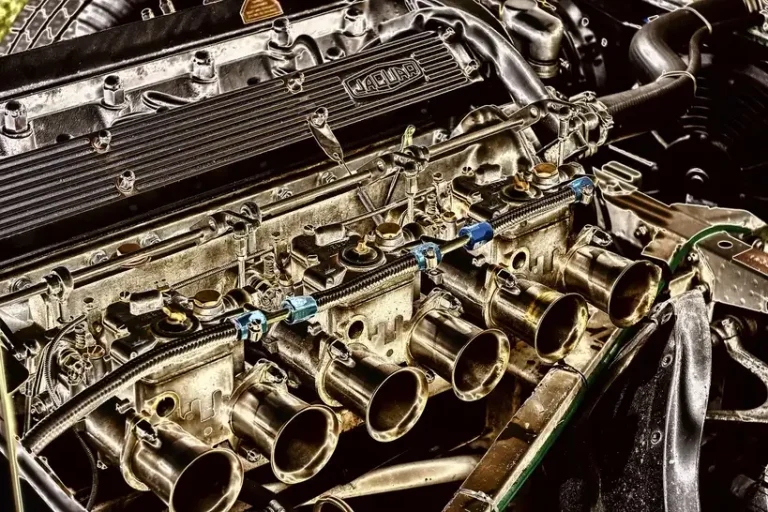 Mechanic comparing driver side and passenger side exhaust manifolds on a garage workbench
