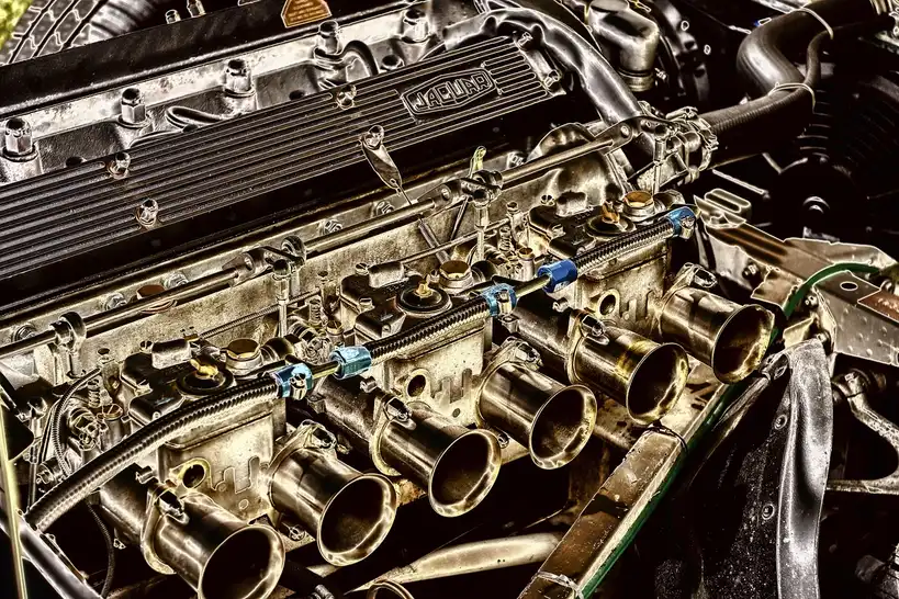 Mechanic comparing driver side and passenger side exhaust manifolds on a garage workbench