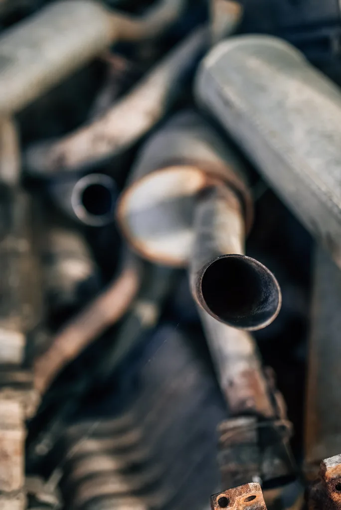 Mechanic comparing an exhaust flange, flat gasket, and crush washer on a workbench