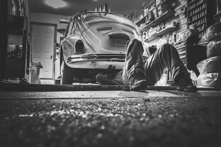 Mechanic inspects a sedan on a lift during an exhaust leak diagnosis in a repair shop