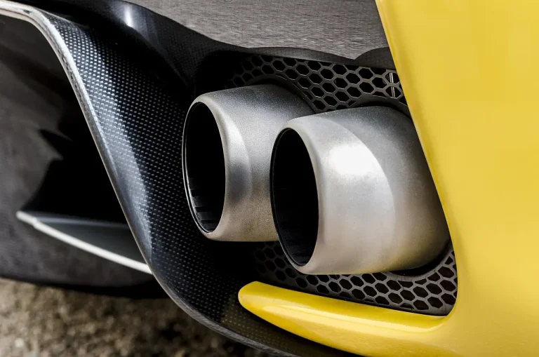 Mechanic inspecting a sedan's exhaust area in natural morning light