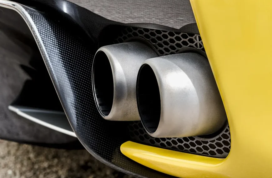 Mechanic inspecting a sedan's exhaust area in natural morning light