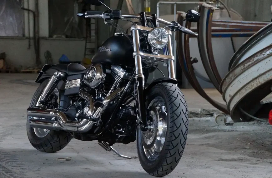 Motorcyclist beside a sport bike with a removed full system motorcycle exhaust on a workbench.