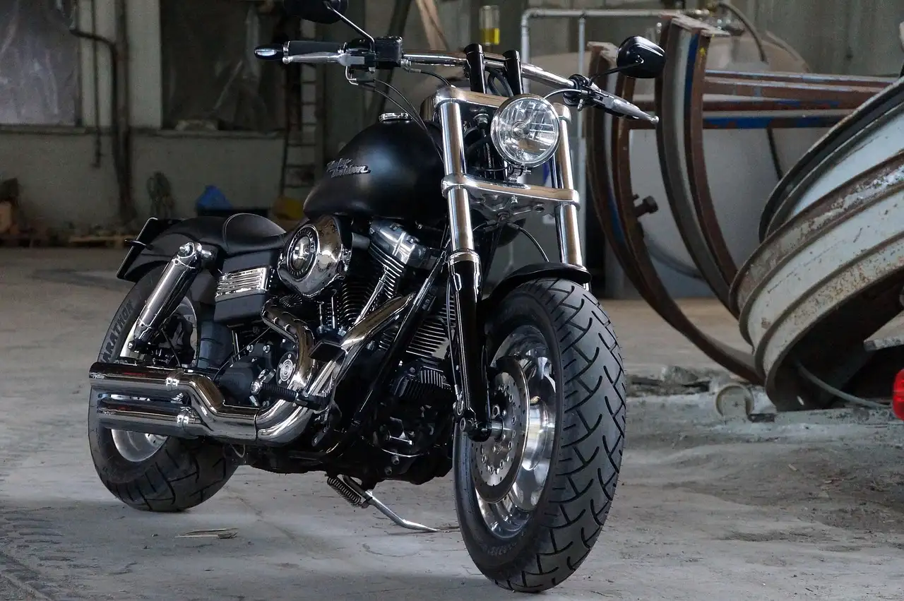 Motorcyclist beside a sport bike with a removed full system motorcycle exhaust on a workbench.