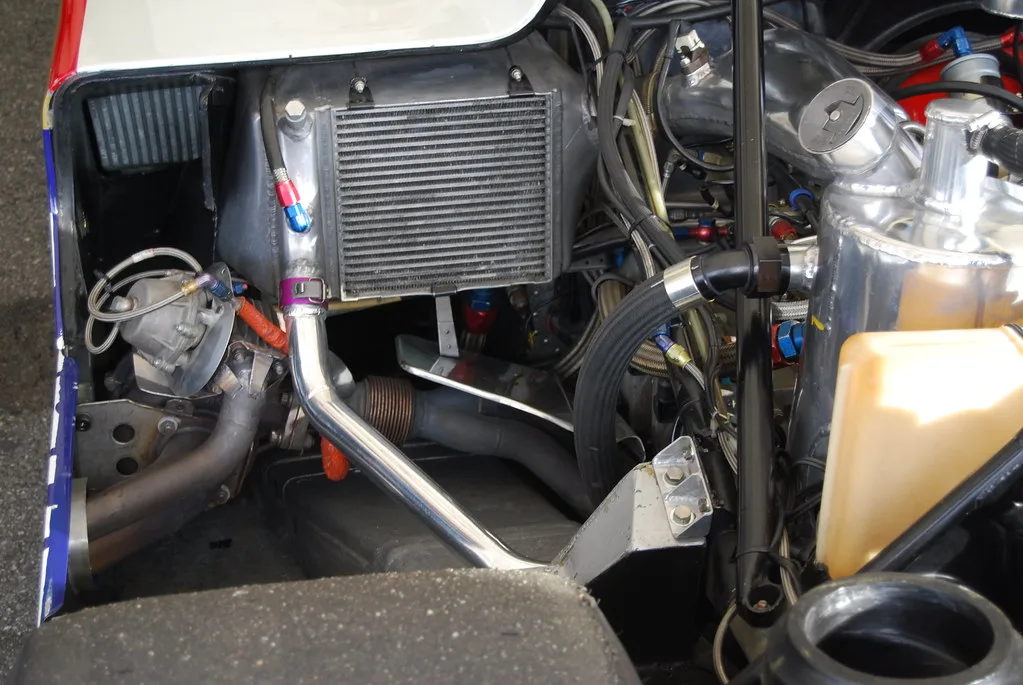 Mechanic inspects heat shields beneath a raised vehicle in a repair bay