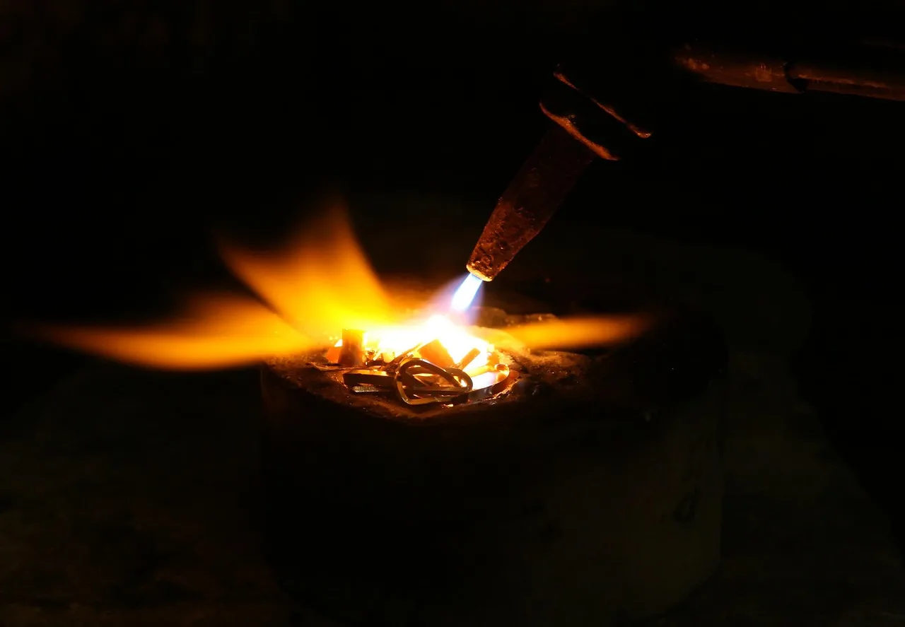 Mechanic welding a custom exhaust pipe beside a lifted car in a repair shop