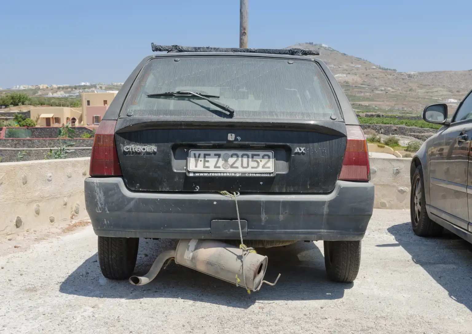 Rusty exhaust pipe flange and catalytic converter connection under a car with a crack visible