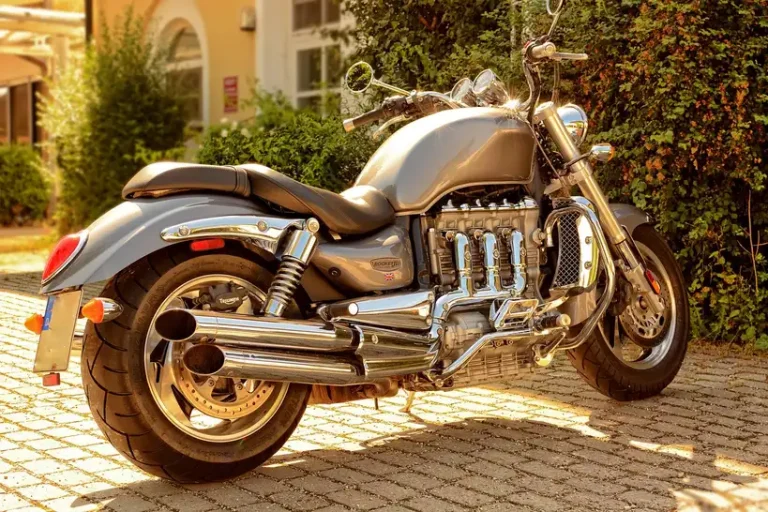 Motorcycle with an aftermarket exhaust being inspected in a sunlit garage