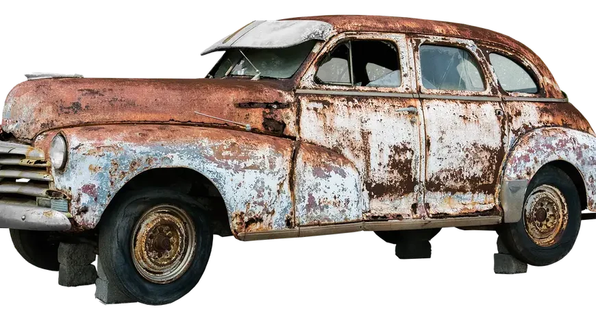 Mechanic inspecting a rusted exhaust pipe under a car on a lift