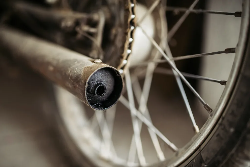 Close-up of motorcycle exhaust parts and calipers on a workbench