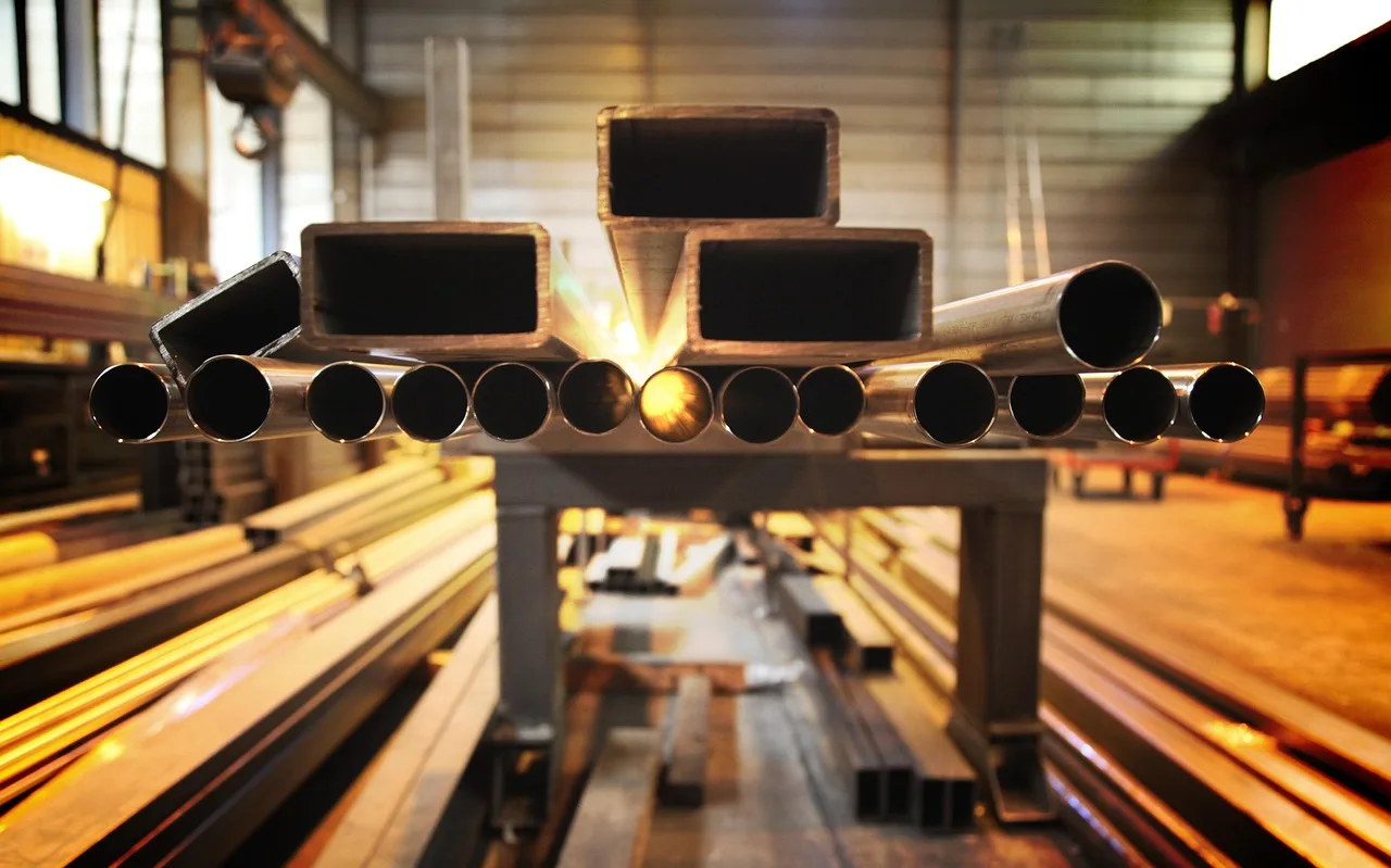 Stainless steel and aluminized exhaust parts side by side in a workshop, showing rust on the aluminized pipe.